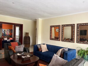Een woonkamer met een blauwe bank, een salontafel en drie spiegels aan de muur.