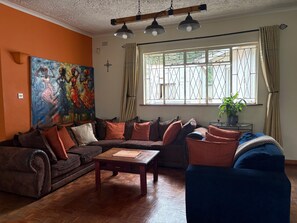 Een woonkamer met een bank, een salontafel, een schilderij en een raam met gordijnen.