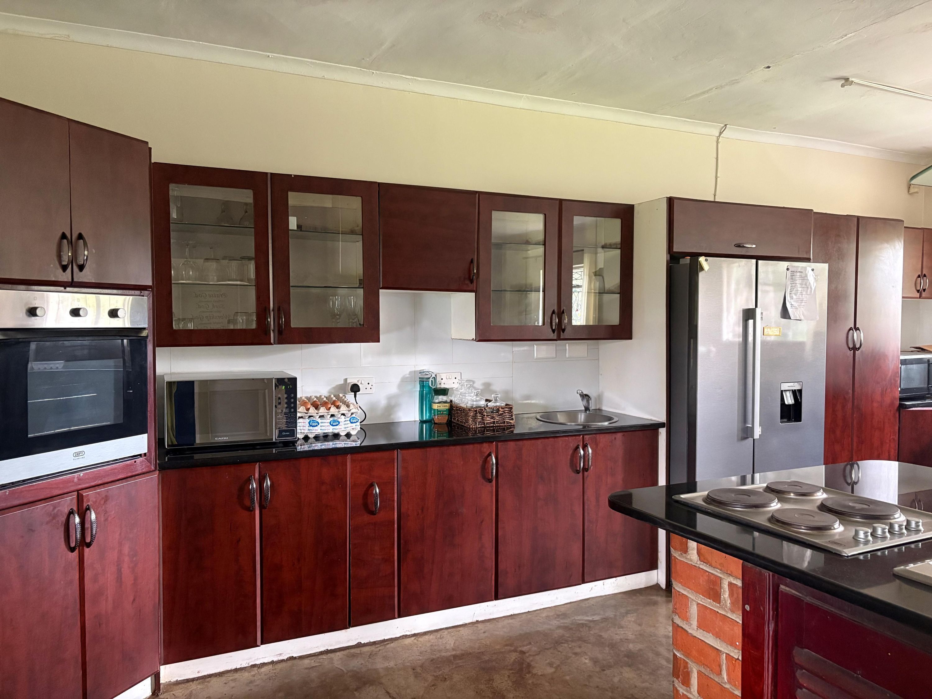 A kitchen with wooden cabinets, a microwave, an oven, a refrigerator, and a sink.