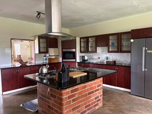 A kitchen with a central island, a built-in oven, and a stainless steel refrigerator. - Double Bedroom In Mt Pleasant Heights - 2378 (Harare)