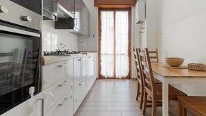 Een moderne keuken met witte kasten, een fornuis en een eethoek met houten stoelen en een tafel.