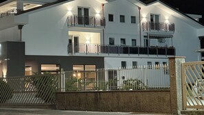 Un immeuble à deux étages doté de balcons, d’une entrée sécurisée par un portail et d’une allée pavée.