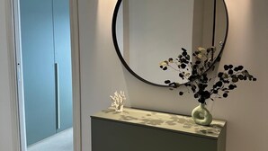 Une salle de bain moderne avec un meuble-lavabo, un miroir rond et un vase de fleurs.