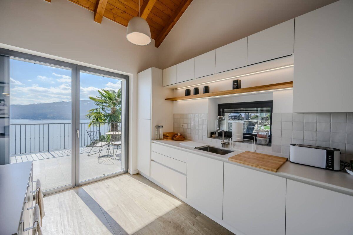 Une cuisine moderne dotée d’une grande porte-fenêtre coulissante qui donne sur un balcon offrant une vue sur la mer.