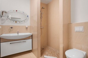Kylpyhuone, jossa on pesuallas, peili, suihku ja wc.