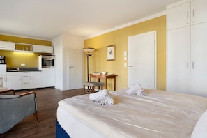 Une chambre d’hôtel comprenant un lit, un bureau, une chaise, un coin cuisine et une armoire.