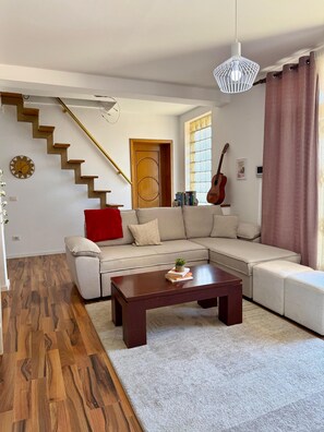 A living room with a wooden staircase, a sofa, a coffee table, and a guitar. - Experience a unique stay in the heart of Shkodër’s most iconic neighborhood. (Shkodër)