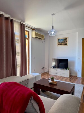 A modern living room with a sofa, a coffee table, a TV, and a painting on the wall. - Experience a unique stay in the heart of Shkodër’s most iconic neighborhood. (Shkodër)