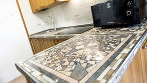 A kitchen with a patterned tile backsplash, a microwave, and wooden cabinets. - Apartment 1 Shared Garden and Wi-Fi (Teola)