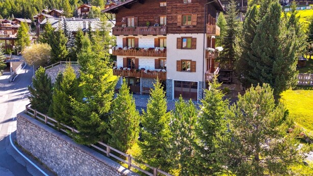 A multi-story building with balconies, surrounded by trees and set against a mountainous backdrop. - Apartment 1 Shared Garden and Wi-Fi (Teola)