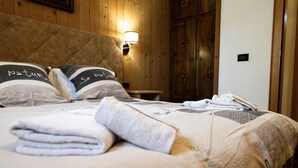 A neatly made bed with a duvet, pillows with text, a bedside lamp, and a folded towel. - Apartment 1 Shared Garden and Wi-Fi (Teola)