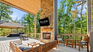 Une terrasse en bois avec des sièges d’extérieur, une cheminée en pierre et un panneau indiquant « Treeline Vacation Rentals ».