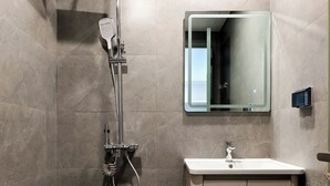 A modern bathroom with a shower, a sink, and a mirror. - Klara House Phuc Dong (Hanoi)