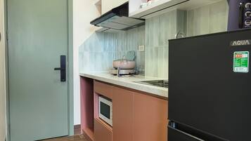 A compact kitchen with a refrigerator, oven, and microwave.