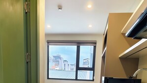 A compact kitchen with a window, a bed, and a green door. - Klara House Phuc Dong (Hanoi)