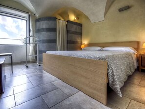 Ein modernes Hotelzimmer mit einem großen Bett, einem Schreibtisch und Blick zum Himmel durch ein Fenster.