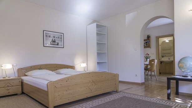A bedroom with a wooden bed, bedside tables, a globe, and a bookshelf.