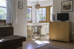 A living room with a sofa, a dining table with chairs, a television, and a wooden cabinet. - 741A Gwürzerhof Apartment (Termeno sulla strada del vino)