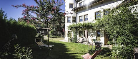 A well-maintained garden with a lawn, a small tree, and a gazebo.