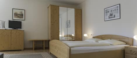 Une chambre à coucher comprenant un lit, des tables de chevet, une armoire, un téléviseur et un tableau encadré accroché au mur.