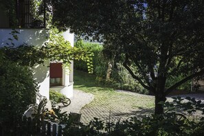 A paved courtyard with a white building, a tree, and a statue. - 741A Gwürzerhof Apartment (Termeno sulla strada del vino)