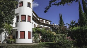 A multi-story building with a white facade and red shutters, surrounded by lush greenery and a clear blue sky. - 741A Gwürzerhof Apartment (Termeno sulla strada del vino)