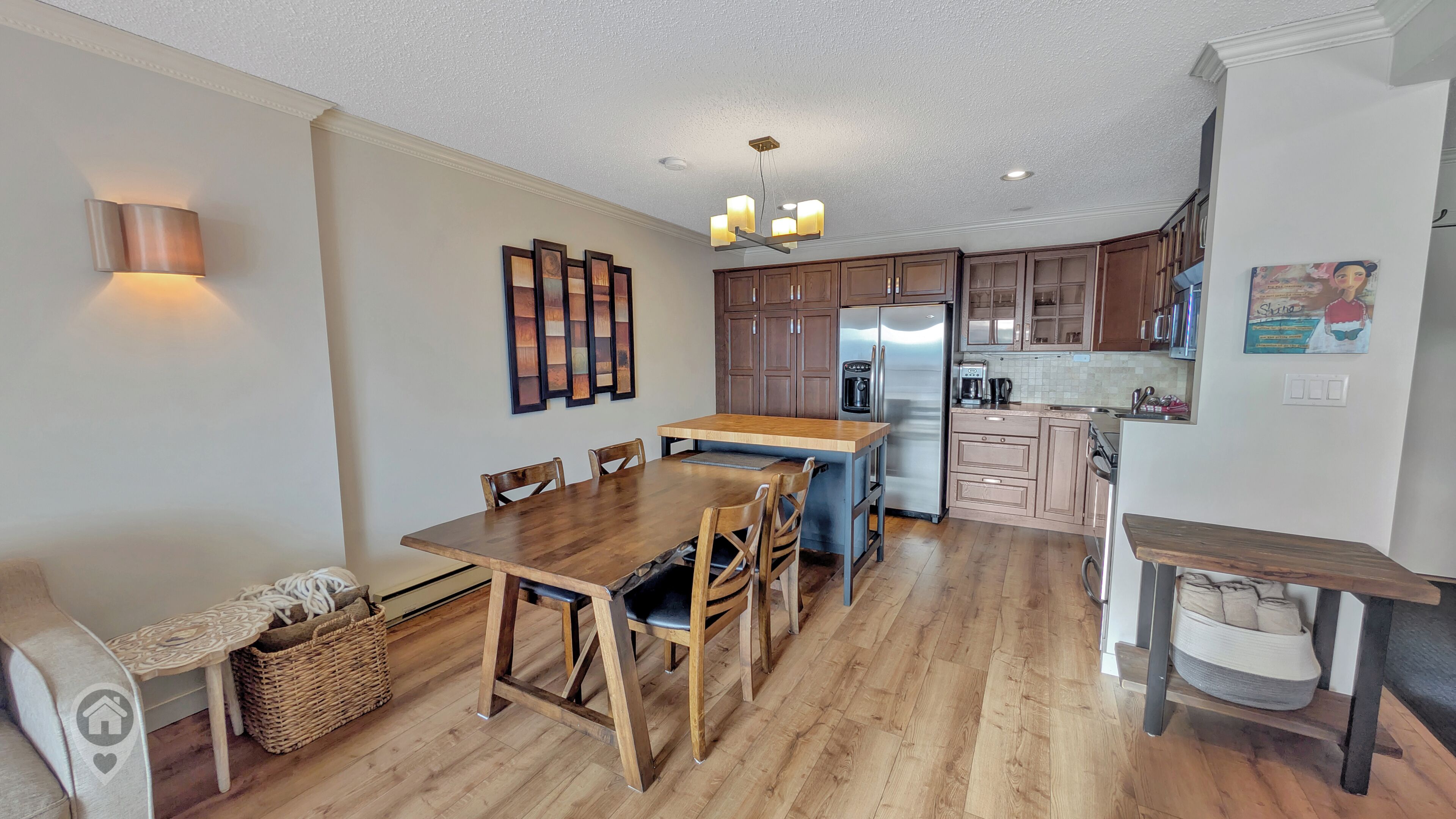 Een moderne keuken met houten kastjes, een centraal eiland en een eethoek met tafel en stoelen.