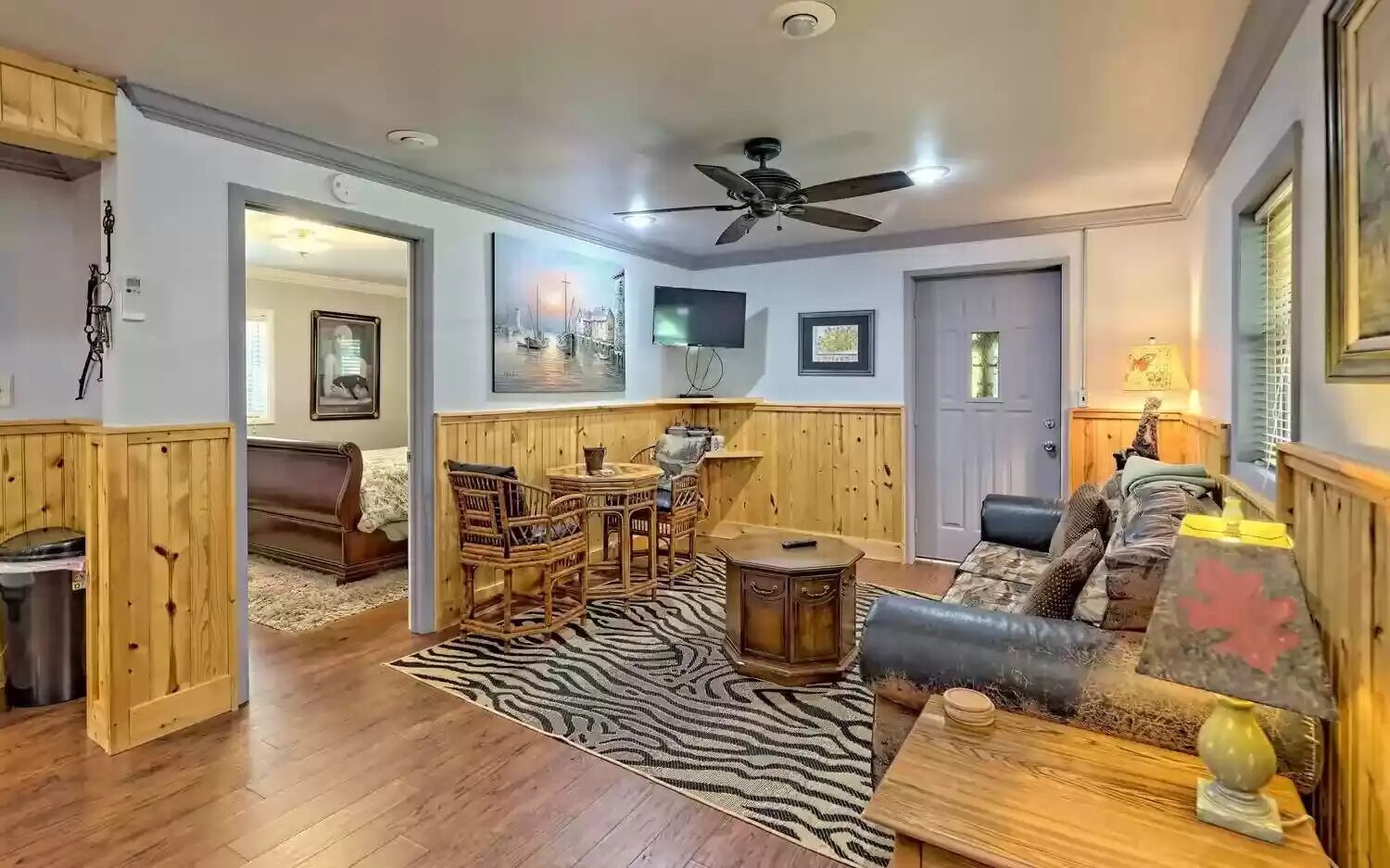 A living room with wooden paneling, a ceiling fan, a zebra-patterned rug, and a sofa.