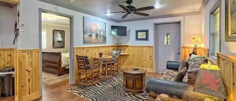 A living room with wooden paneling, a ceiling fan, a zebra-patterned rug, and a sofa.