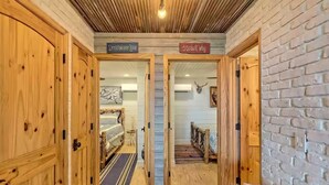 Um corredor com portas de madeira identificadas como 'Dreamweaver Lane' e 'Stardust Way', conduzindo a quartos com camas e uma decoração de cabeça de veado.