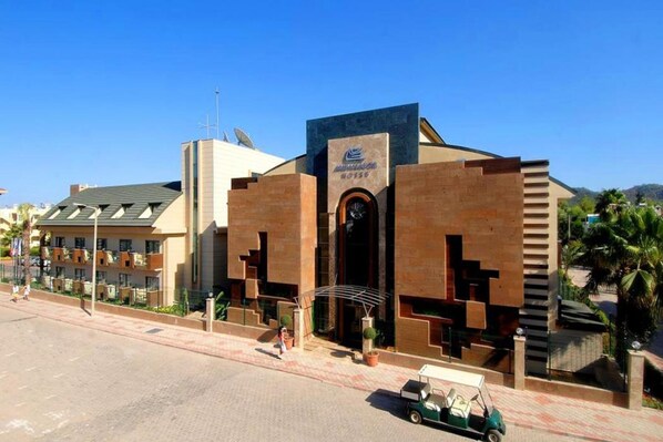Un edificio moderno con una entrada destacada, un letrero sobre la puerta y un carrito de golf estacionado al frente.