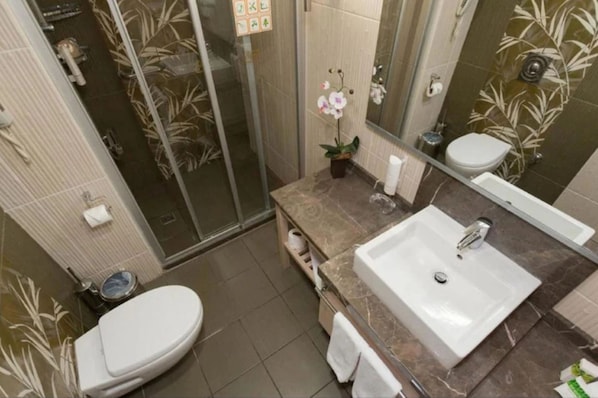 A bathroom with a shower, toilet, sink, and a mirror. - Ambassador Plaza Hotel (Kemer)