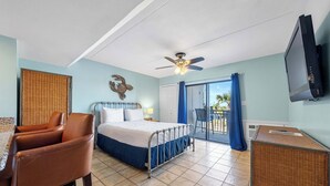 Una habitación con cama, sillón, televisor y balcón con vistas.