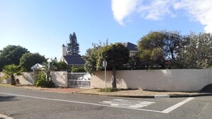 A street with a pedestrian crossing, a white wall, and a gated area with a fence. - Misasa on Orchard - Quarto Duplo Deluxe com Varanda 2 (Cape Town)