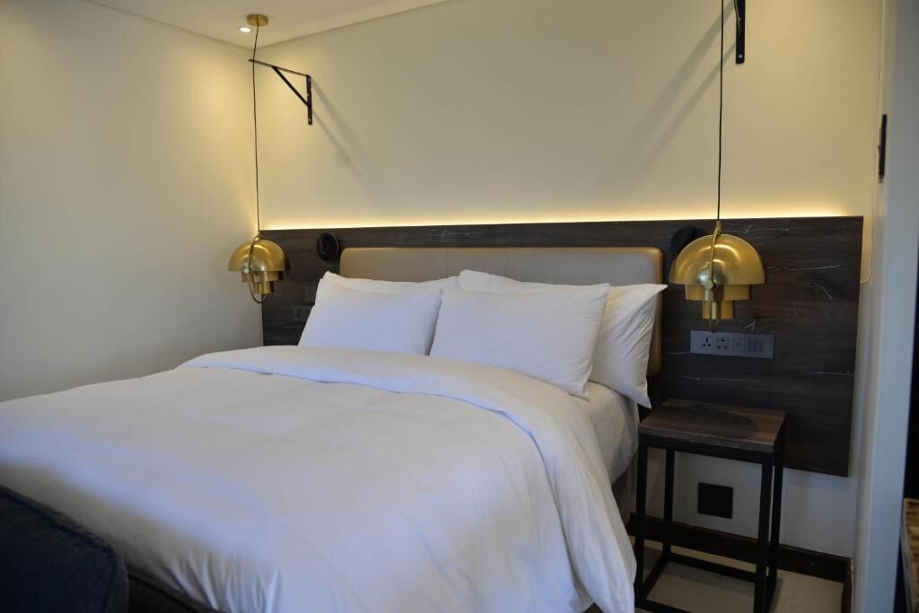 A modern hotel room with a large bed, two bedside lamps, and a small table.