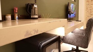 A kitchenette with a coffee maker, a TV, and a chair. - Misasa on Orchard - Quarto Duplo Deluxe com Varanda 2 (Cape Town)