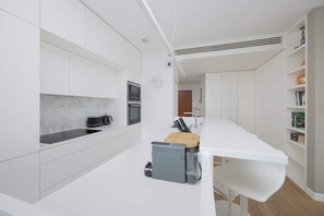 Eine moderne Küche mit weißen Schränken, einer Marmor-Spritzschutzwand und einem eingebauten Ofen.