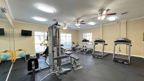 Une salle de sport équipée de divers appareils d’exercice, notamment des tapis de course, des appareils de musculation et un vélo d’appartement.