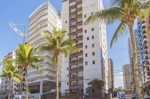 A multi-story building with balconies, palm trees, and a clear sky. - Apto em Praia Grande Frente a Praia da Guilhermina (Praia Grande)