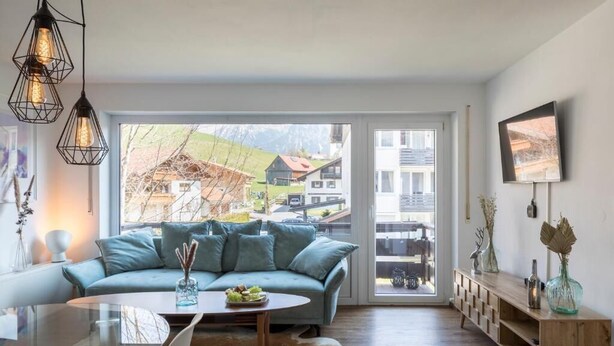Uma sala de estar moderna com sofá, mesa de centro e mesa de jantar de vidro.