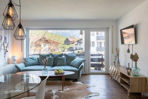 A modern living room with a sofa, coffee table, and a glass dining table. - Apartment Alpenglühen nahe Breitachklamm (Oberstdorf)