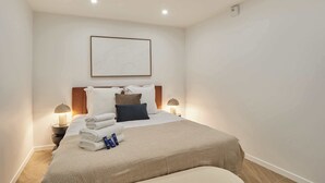 A hotel room with a bed, bedside lamps, a framed artwork on the wall, and neatly folded towels. - Modern Apartment Center of Paris Montmartre (Paris)