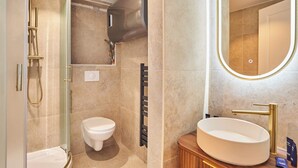 A modern bathroom with a glass-enclosed shower, a toilet, and a vanity with a sink and mirror. - Modern Apartment Center of Paris Montmartre (Paris)