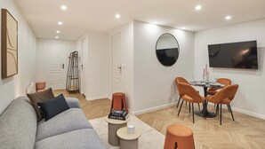 A modern living room with a sofa, coffee table, and dining area with chairs. - Modern Apartment Center of Paris Montmartre (Paris)