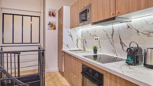 A modern kitchen with wooden cabinets, a built-in microwave, a stainless steel kettle, and a dishwasher. - Beautiful apartment in the heart of Paris 10 people (Paris)