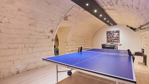 A ping pong table in a room with exposed brick walls and a ceiling with exposed beams. - Beautiful apartment in the heart of Paris 10 people (Paris)