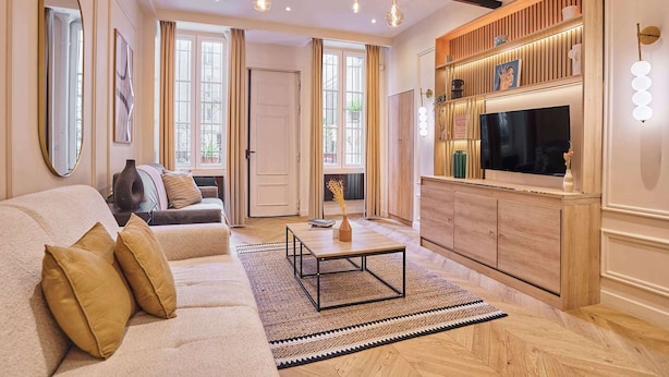 A living room with a sofa, coffee table, TV, and wooden shelving. - Beautiful apartment in the heart of Paris 10 people (Paris)
