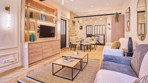 A modern living room with a TV, wooden shelving, a dining area, and a sofa. - Beautiful apartment in the heart of Paris 10 people (Paris)