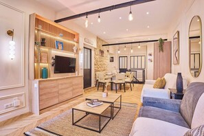 Ein modernes Wohnzimmer mit Fernseher, Holzregalen, einem Essbereich und einer Couch.