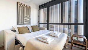 Un dormitorio moderno con una cama grande, vistas al exterior y una obra de arte geométrica en la pared.